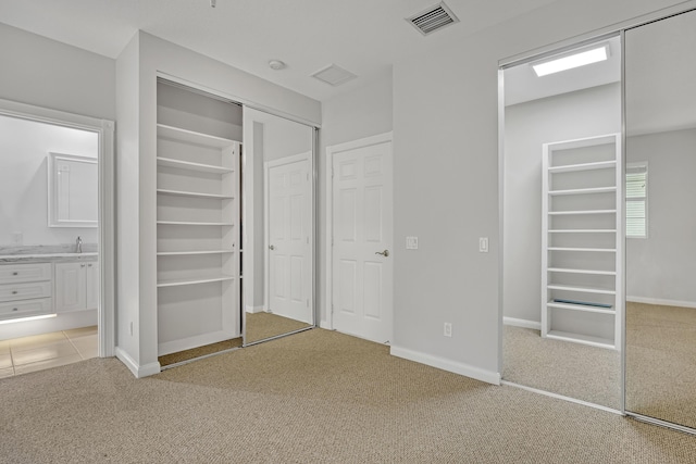 3216 W Community Dr, Jupiter, FL 33458 - unfurnished bedroom with light carpet, two closets, ensuite bath, baseboards, and a sink