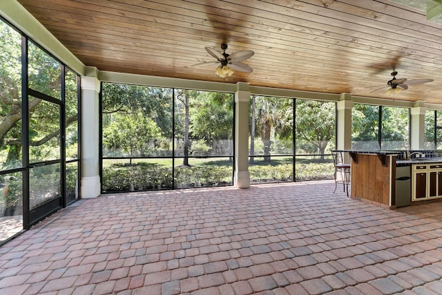 unfurnished sunroom with brick floor, wooden ceiling, and a wealth of natural light