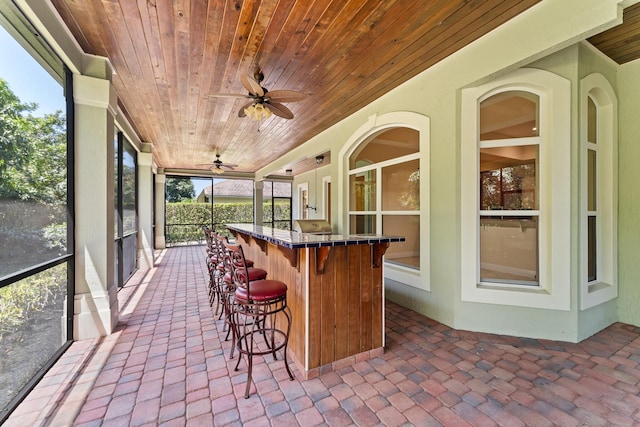 sunroom featuring ceiling fan and outdoor dry bar