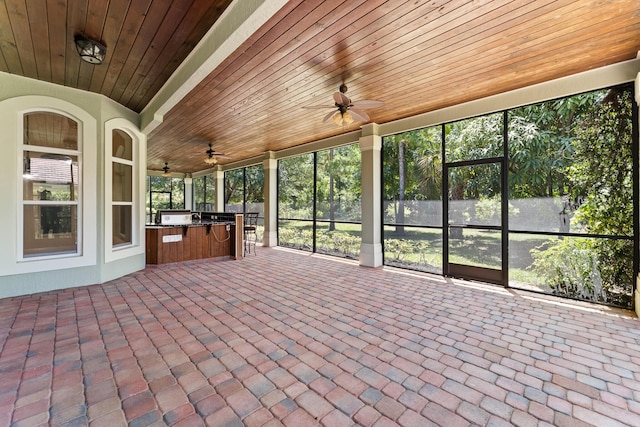 unfurnished sunroom featuring an outdoor kitchen and ceiling fan