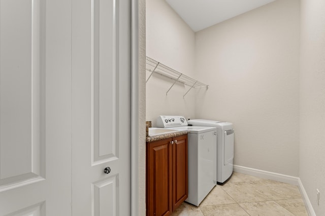laundry room with light tile patterned flooring, baseboards, washer and clothes dryer, and cabinet space