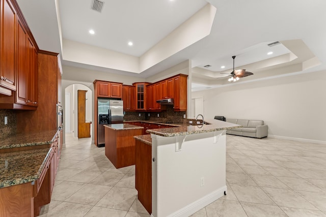 kitchen featuring arched walkways, a raised ceiling, visible vents, and stainless steel fridge with ice dispenser