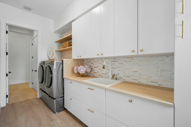 5214 SW Pomegranate Way, Palm City, FL 34990 - washroom featuring cabinet space, a sink, light wood-style floors, visible vents, and washer and clothes dryer