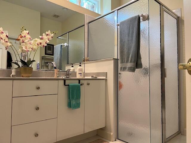 full bath with a shower stall, vanity, and visible vents