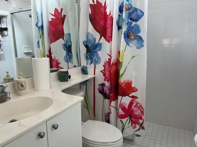 full bath with toilet, vanity, and a stall shower