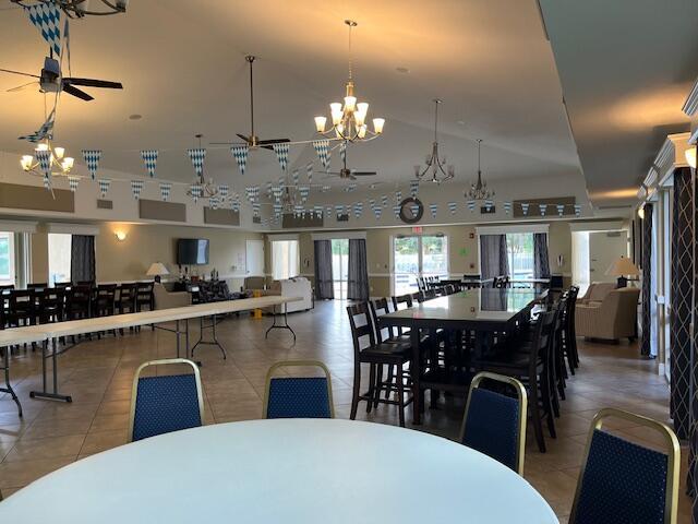 dining room with tile patterned floors and ceiling fan with notable chandelier