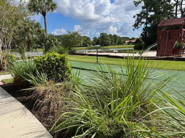 view of home's community featuring a lawn, a water view, and playground community