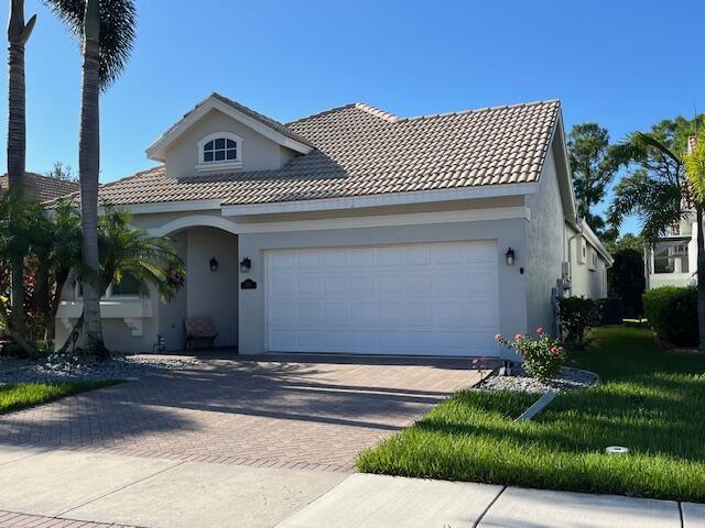 mediterranean / spanish home featuring an attached garage, a tiled roof, stucco siding, and decorative driveway