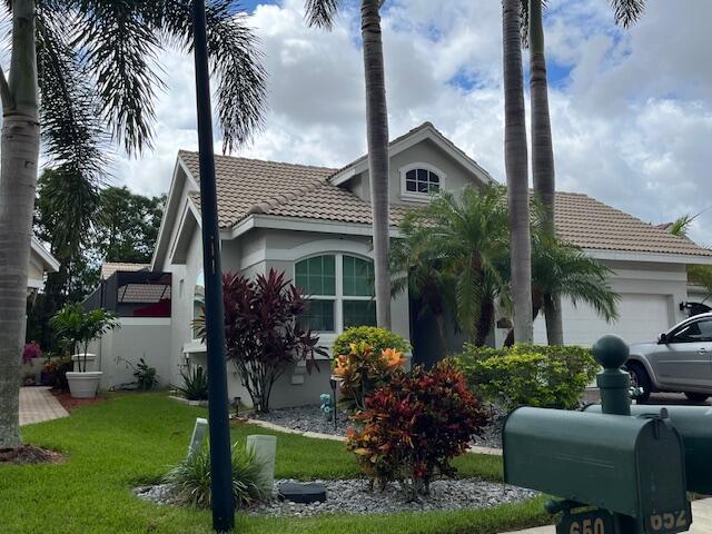 view of property exterior featuring an attached garage, a tiled roof, stucco siding, and a lawn