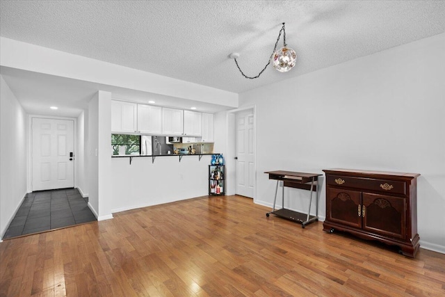 3526 Whitehall Dr Unit 106, West Palm Beach, FL 33401 - kitchen featuring white cabinets, fridge, wood finished floors, a textured ceiling, and a chandelier
