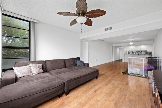 3526 Whitehall Dr Unit 106, West Palm Beach, FL 33401 - living room featuring light wood-style floors, ceiling fan, a textured ceiling, and a wall of windows