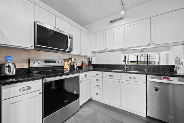 3526 Whitehall Dr Unit 106, West Palm Beach, FL 33401 - kitchen with appliances with stainless steel finishes, a sink, white cabinetry, tasteful backsplash, and a textured ceiling