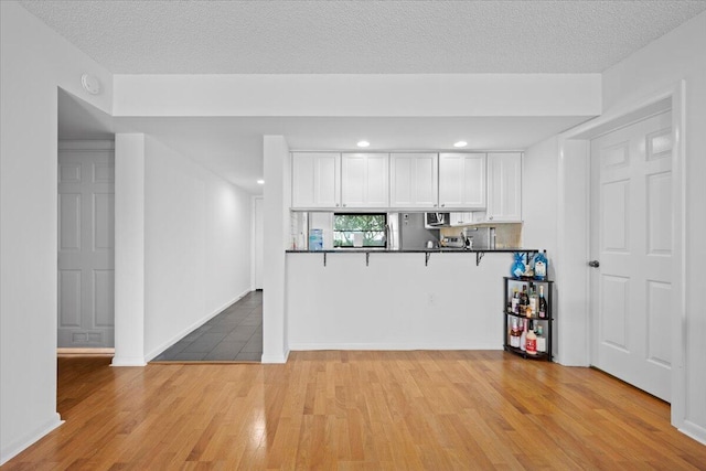 3526 Whitehall Dr Unit 106, West Palm Beach, FL 33401 - kitchen with white cabinetry, light wood-style floors, dark countertops, recessed lighting, and a textured ceiling