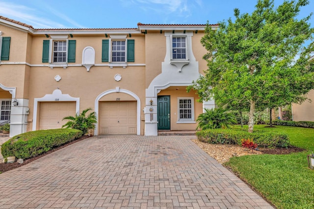 view of front of home with stucco siding, decorative driveway, and a garage