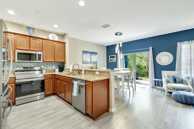 kitchen featuring visible vents, light wood-type flooring, a sink, a peninsula, and stainless steel appliances