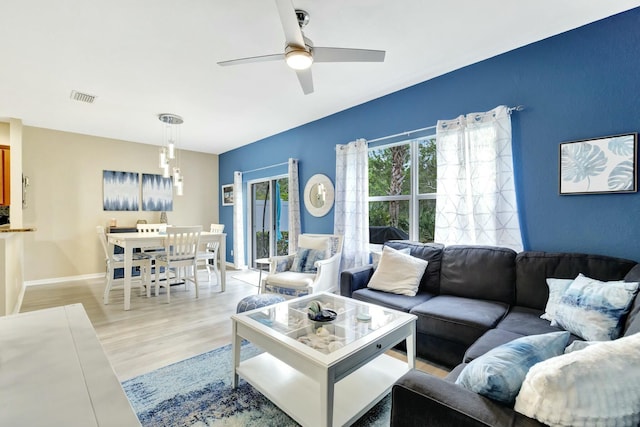 living area featuring a ceiling fan, baseboards, visible vents, and light wood finished floors