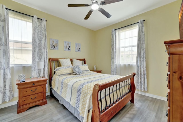 bedroom with light wood-style floors, a ceiling fan, and baseboards