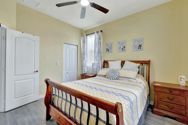 bedroom featuring visible vents, a closet, wood finished floors, baseboards, and a ceiling fan