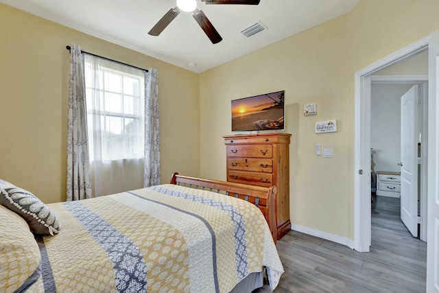 bedroom with a ceiling fan, baseboards, visible vents, and wood finished floors