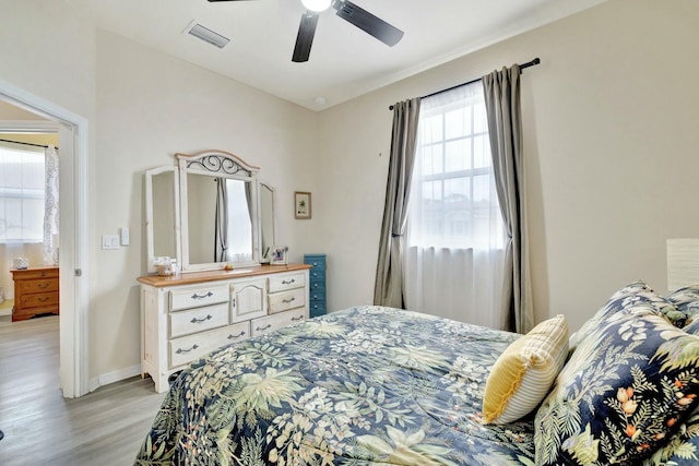 bedroom featuring light wood-style floors, baseboards, ceiling fan, and visible vents