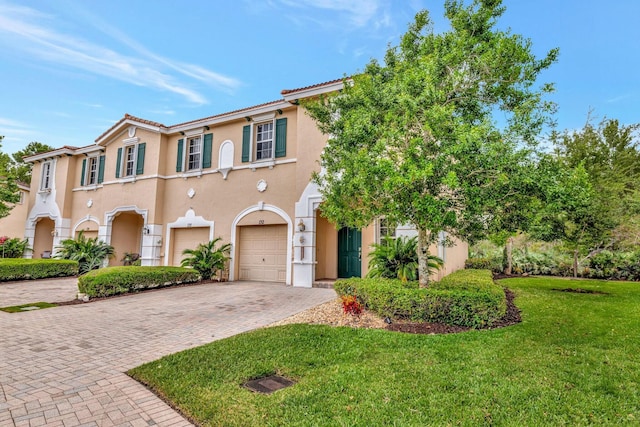 view of front of property with a garage, a front yard, decorative driveway, stucco siding, and a tile roof