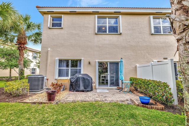 rear view of property featuring a lawn, a patio area, central AC, fence, and stucco siding