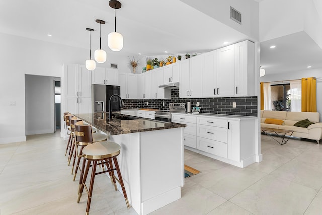 kitchen featuring tasteful backsplash, a sink, stainless steel appliances, white cabinetry, and visible vents