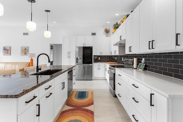 kitchen with a sink, visible vents, backsplash, under cabinet range hood, and appliances with stainless steel finishes