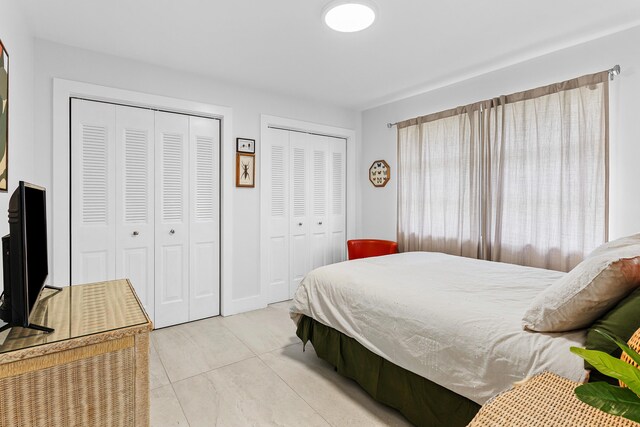 tiled bedroom featuring multiple closets
