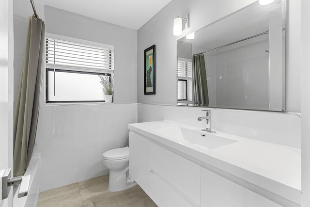 bathroom with vanity, shower / tub combo with curtain, tile walls, a wainscoted wall, and toilet