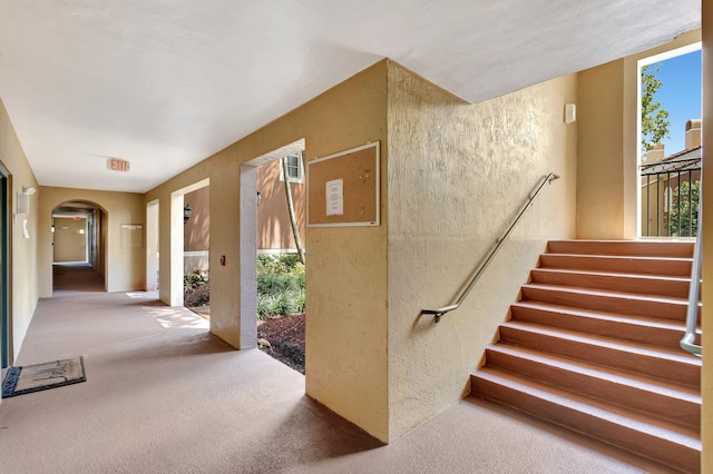 11760 Saint Andrews Pl Unit 204, Wellington, FL 33414 - stairs featuring arched walkways, a textured wall, and carpet flooring