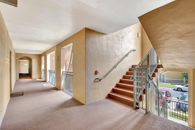 11760 Saint Andrews Pl Unit 204, Wellington, FL 33414 - stairway with arched walkways, a textured wall, carpet flooring, and a healthy amount of sunlight