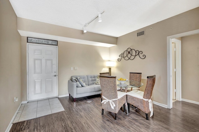 11760 Saint Andrews Pl Unit 204, Wellington, FL 33414 - dining area featuring wood finished floors, a textured ceiling, rail lighting, baseboards, and visible vents