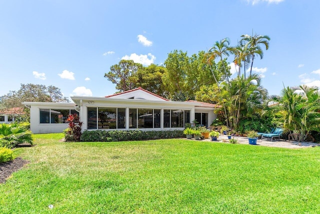 back of property with a sunroom, a lawn, and stucco siding