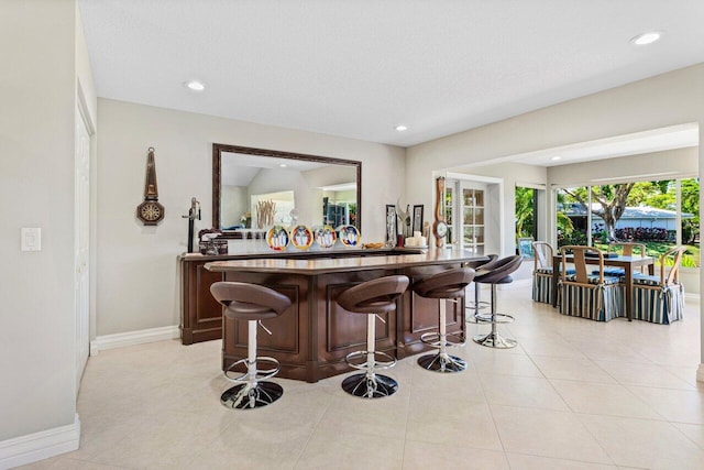 bar featuring baseboards, a dry bar, light tile patterned floors, and recessed lighting