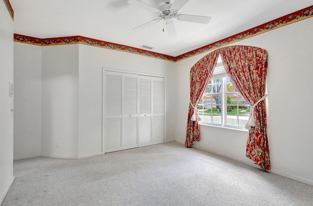 unfurnished bedroom with a closet, baseboards, carpet flooring, ceiling fan, and visible vents