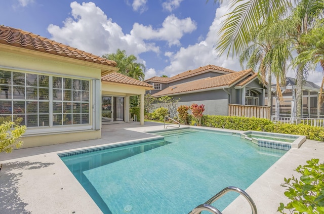 view of swimming pool with a patio, a pool with connected hot tub, and fence