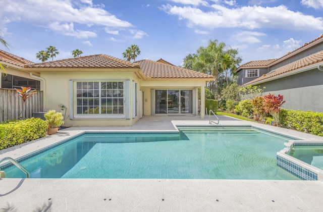 view of swimming pool featuring a pool with connected hot tub, a patio area, and fence