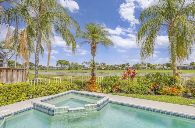 view of swimming pool with a water view, a pool with connected hot tub, and fence