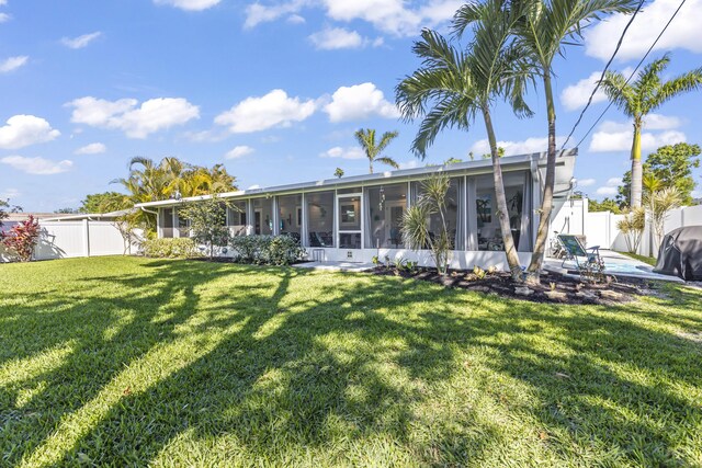 rear view of house with a fenced backyard, a sunroom, and a yard
