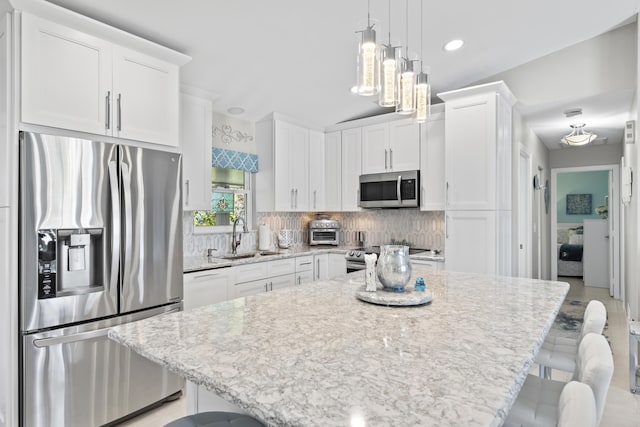 kitchen with white cabinets, a breakfast bar, a sink, and appliances with stainless steel finishes