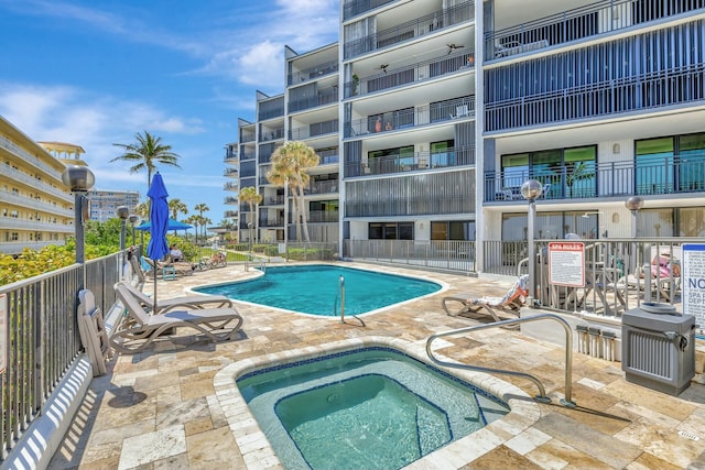 pool featuring a patio area, a hot tub, and fence