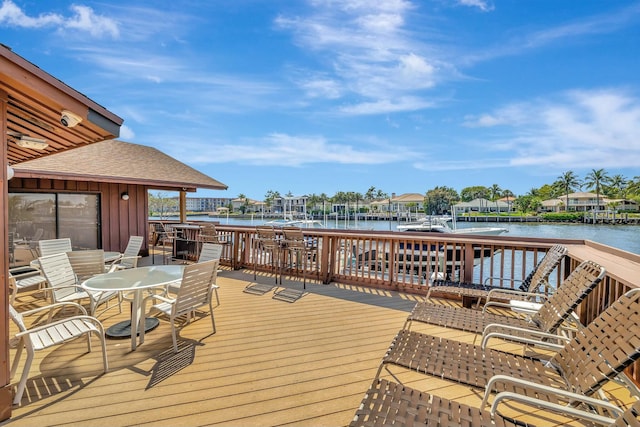 wooden terrace with outdoor dining space and a water view