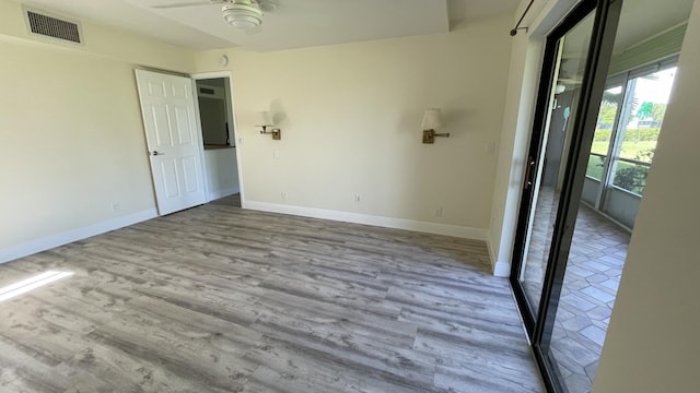 unfurnished room featuring baseboards, visible vents, wood finished floors, and a ceiling fan