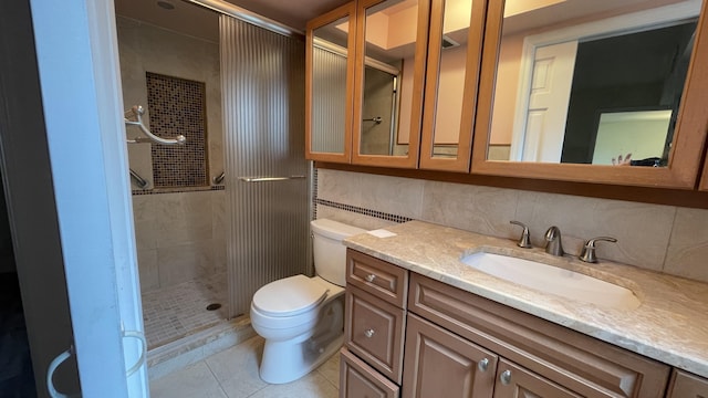 bathroom with a shower stall, toilet, vanity, and tile patterned floors