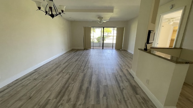 unfurnished dining area featuring wood finished floors and ceiling fan with notable chandelier