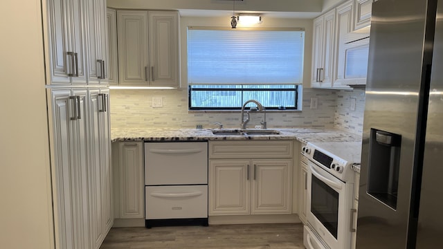 kitchen with a sink, decorative backsplash, wood finished floors, white appliances, and light stone counters
