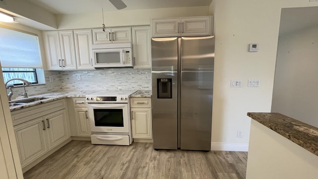 kitchen featuring light wood finished floors, white appliances, a sink, and tasteful backsplash