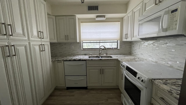 kitchen with light stone counters, wood finished floors, a sink, white appliances, and tasteful backsplash