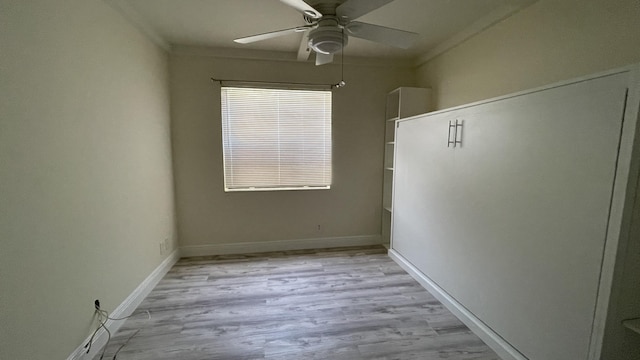 empty room with ornamental molding, ceiling fan, baseboards, and light wood-type flooring